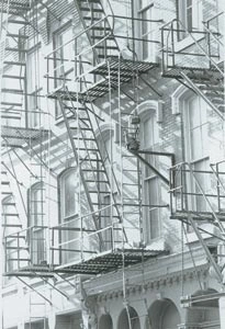 Black-and-white photograph of overlapping metal fire escapes on a building