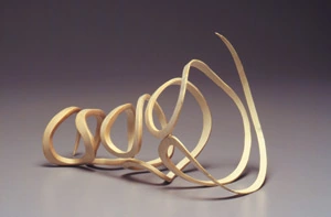 Photograph of a pale wooden sculpture made of looping curved forms
